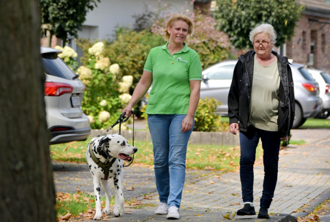 Mitarbeiterin geht mit Kundin und Hund Gassi